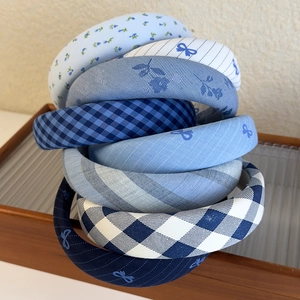 Close-up detail of blue plaid and floral padded headbands with bow patterns on a tray