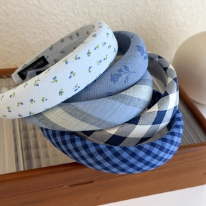 Detail of four blue plaid and floral sponge headbands with handmade labels on wood tray