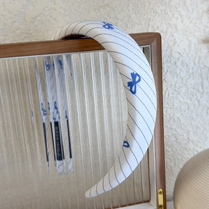 Detail view of a blue plaid bow headband with a handmade label on thick sponge padding