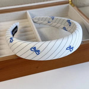 Detail of blue bow pattern fabric headband with handmade tag in a wooden gift box