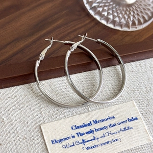 Detailed view of silver hoop earrings with mirror finish on a rustic wooden tray