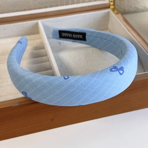 Detail shot of a blue plaid bow headband featuring a handmade label and soft cotton fabric