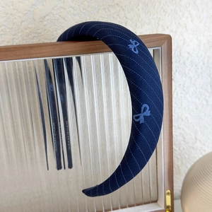 Detail of handmade deep blue plaid sponge headband with light blue stripes and bow pattern