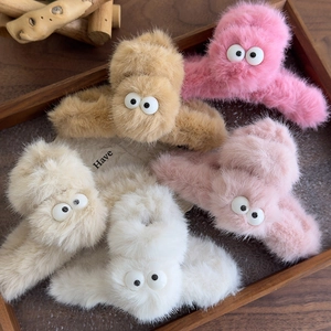 Plush faux fur claw clips with cartoon eyes in five colors on a wooden tray