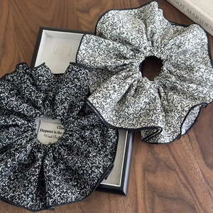 Détail de chouchous à fleurs surdimensionnés avec liseré noir et texture souple