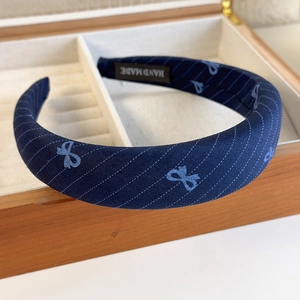 Detail shot of a blue checkered headband with handmade label in a wooden jewelry box
