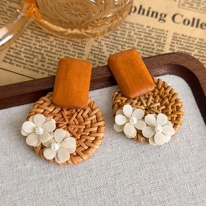Detailaufnahme der handgefertigten Strohohrringe mit Holzplättchen und weißen Stoffblumen