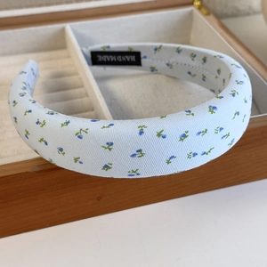 Detailed macro of handmade light blue floral headband padding with HAND MADE woven label