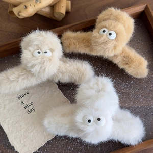 Detailed close-up of fluffy plush claw clips with cute eye designs in three warm colors