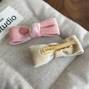 Detailed view of pink and champagne velvet bow hair clips with metal alligator clips