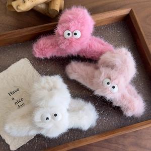 Detailed view of three plush monster hair claws with big eyes on a wooden tray