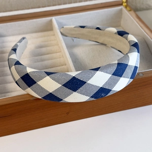 Detailed close-up of blue plaid sponge headband with thick padding in a wooden box