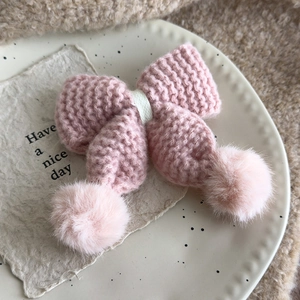 Süße rosa gestrickte Schleifen-Haarspange mit flauschigen Bommeln auf Dekoteller