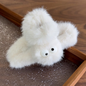 Macro detail of large white plush claw clip featuring cute big cartoon eye decorations