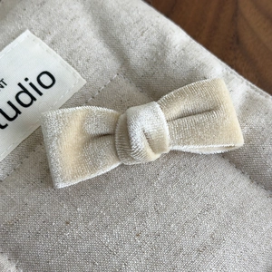 Detail of light beige velvet bow hair clip attached to a rustic linen storage bag