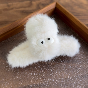 Close-up of white plush shark clip with big eyes on a warm brown textured glass tray