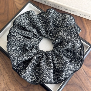 Gros plan sur un grand chouchou à motif floral vintage avec des détails plissés