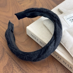 Detail of a thick black knit headband with soft plush texture on a vintage book