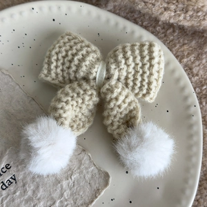 Nahaufnahme der beigen Strickschleife Haarspange mit weißen Pompons für den Winter