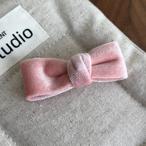 Macro detail of the soft pink velvet material and 3D bow design on the hair clip