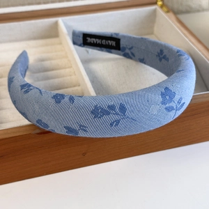 Close-up of blue floral fabric headband with handmade label inside a jewelry box