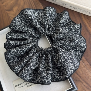 Vue macro détaillée d'un chouchou géant noir avec des motifs floraux blancs classiques