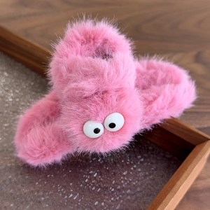 Detail view of the pink plush hair claw clip with large cute eyes and soft furry texture