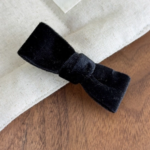 Close-up of black velvet bow hair clip showing fine fabric texture and neat knot