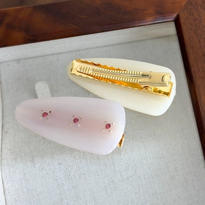Detail of French vintage acetate duckbill hair clips with pink rhinestones set on fabric