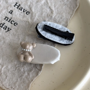 Detailansicht der cremefarbenen 3D-Bären-Haarklammer mit Perle und Metall-Entenschnabelclip