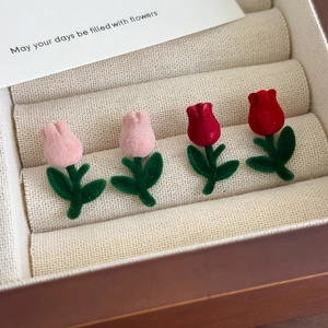 Macro shot of red and pink velvet tulip earrings with green leaves in a jewelry box