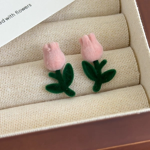 Close-up of pink velvet tulip earrings with green leaves in a jewelry box