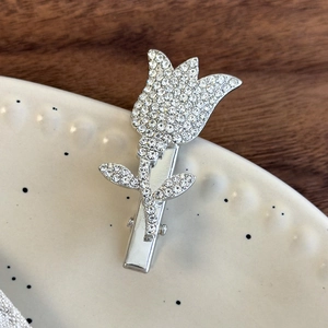 Close-up of a silver tulip hair clip with sparkling rhinestones on a ceramic dish