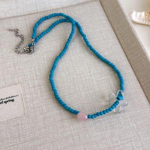Detail der himmelblauen Perlenkette mit transparentem Blumenanhänger und rosa Perle