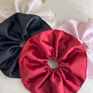 Gros plan de chouchous en satin dans les couleurs bordeaux, noir, beige et rose