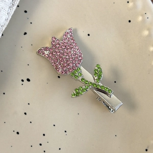 Macro shot of tulip hair clip with sparkling pink and green rhinestones on ceramic