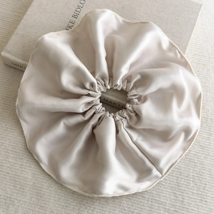 Détail d'un chouchou en satin champagne montrant la texture soyeuse sur un livre