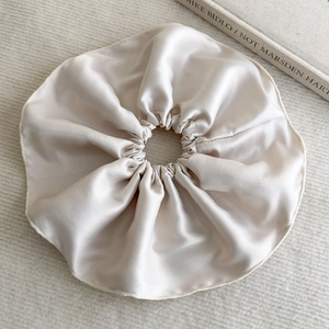 Détail d'un chouchou en satin champagne avec texture soyeuse et bande élastique