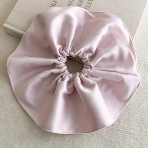 Détail d'un chouchou en satin rose pâle avec plis soyeux sur un fond chaleureux
