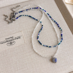 Detail einer zweilagigen Perlenkette mit blauem Herzanhänger und verstellbarer Kette