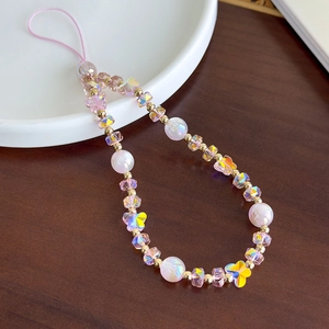 Détail de perles de cristal roses et papillons dorés sur une lanière de téléphone