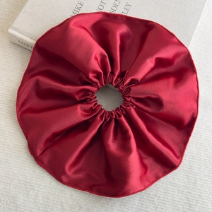 Détail macro du chouchou en satin rouge foncé montrant la texture soyeuse et couture