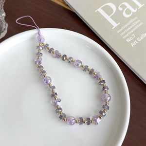 Gros plan de perles en verre violettes et breloque papillon sur le cordon de téléphone