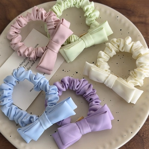 Pastel bow scrunchies in five colors displayed on a polka dot ceramic plate