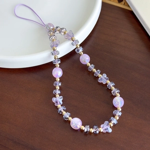 Détail de la lanière de téléphone en perles de verre violettes et papillon avec accents dorés