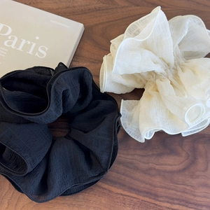 Détail de grands chouchous en mousseline noirs et blancs sur une surface en bois sombre