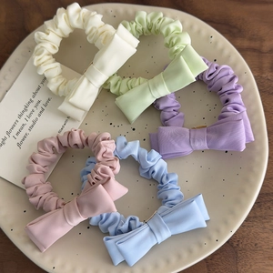 Set of 5 pastel bow scrunchies in cream, purple, pink, blue and green on a tray