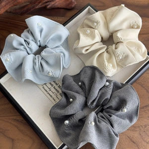 Detail of floral embossed fabric scrunchies with pearls in blue, white and grey colors
