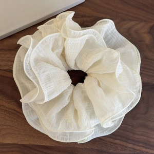 Vue détaillée du tissu en mousseline blanc cassé et des bords volantés du chouchou plissé