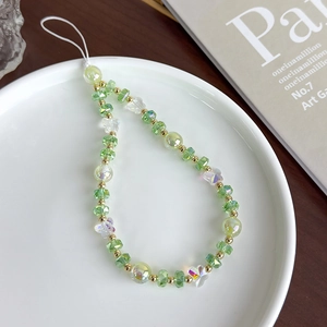 Détail de perles en verre colorées et breloque papillon sur un bijou de téléphone fait main